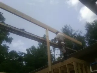 Carpenter setting a ridge beam over a new addition frame — Ice Dam Removal by Roofing Brothers in Burgoon