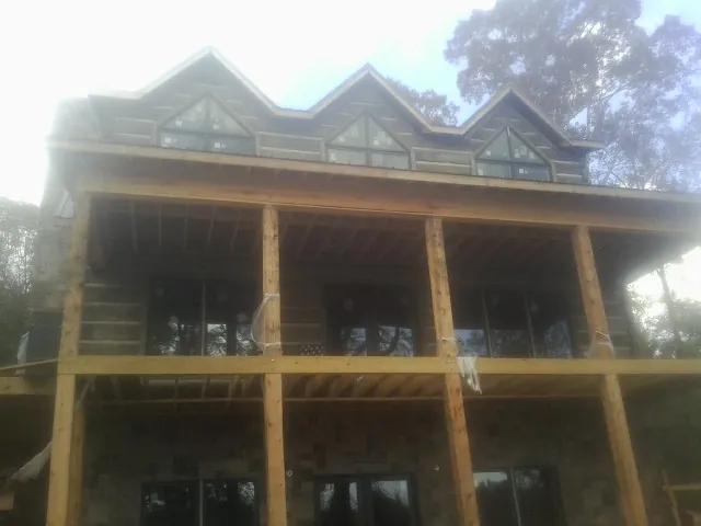 Dormers and porch framing on a large log home under construction — Roof Coating work by our crew in Burgoon