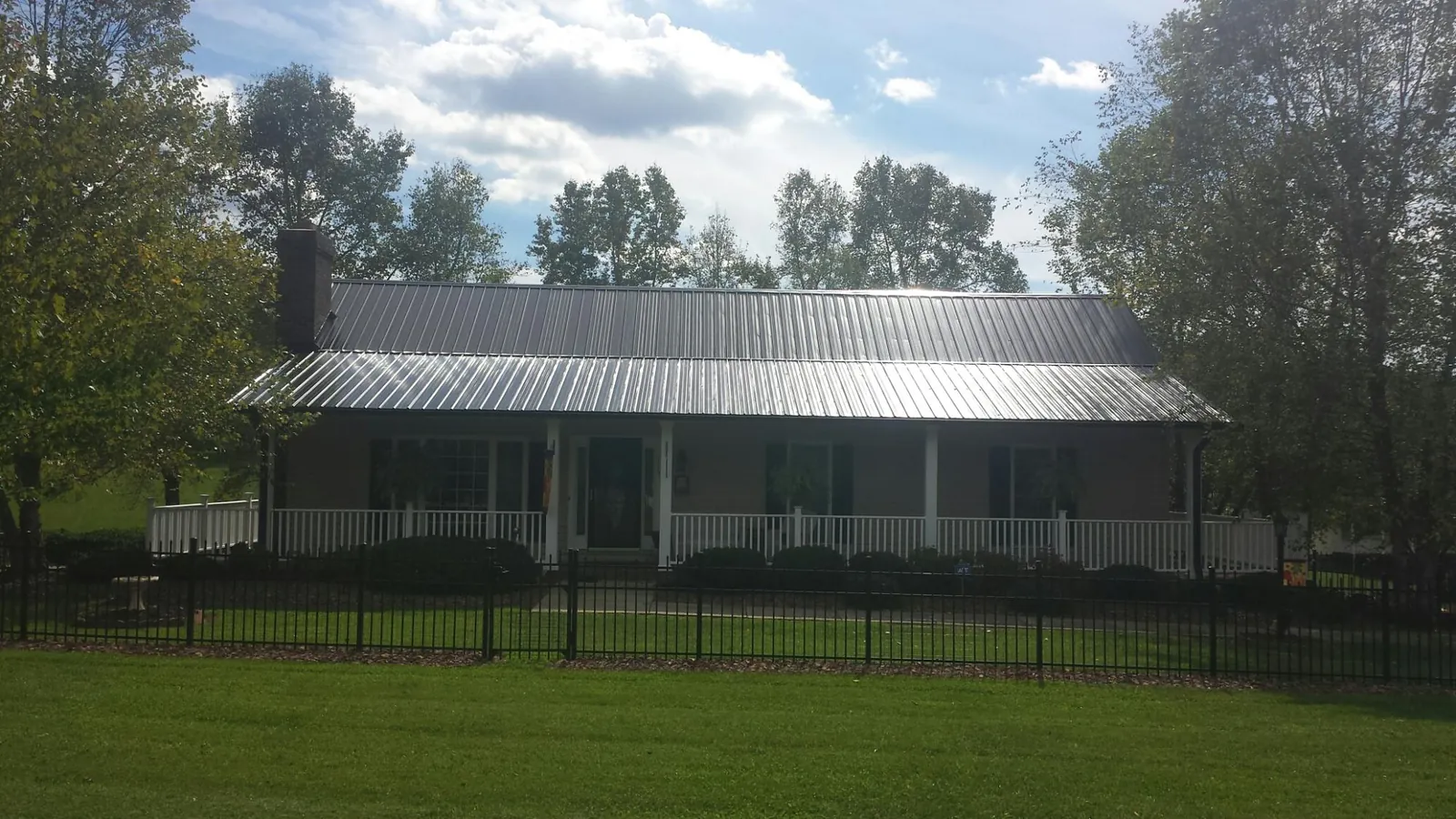 Gray metal roof on a brick ranch with a full width front porch — Gutter Guard Installation work by our crew in Burgoon