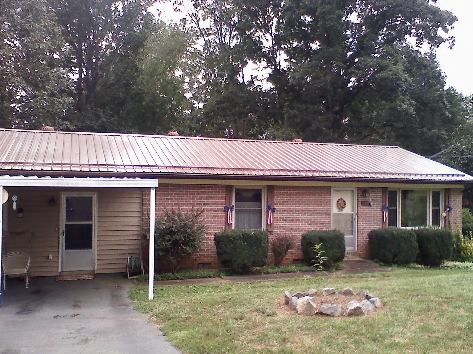 Bronze metal roof and carport on a brick ranch home — Roof Repair work by our crew in Burgoon