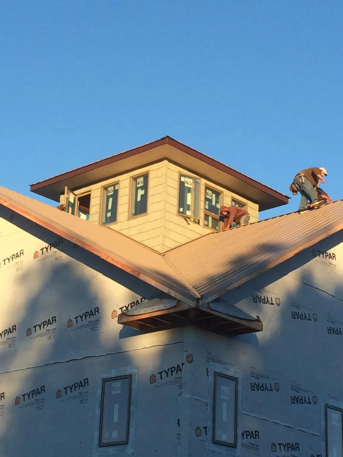 Roofers working around a rooftop cupola on a new metal roof at sunset — Roof Waterproofing in Burgoon by Roofing Brothers